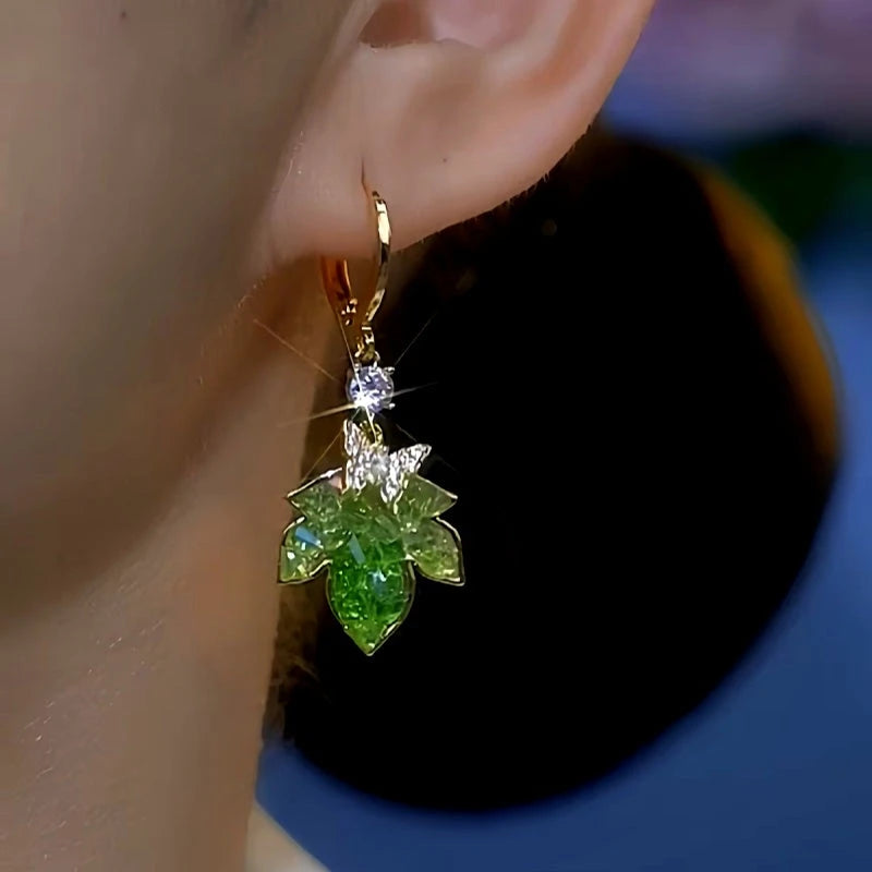 Model showcasing the dangle and style of the 14K Gold-Plated Green Zircon Maple Leaf Earrings