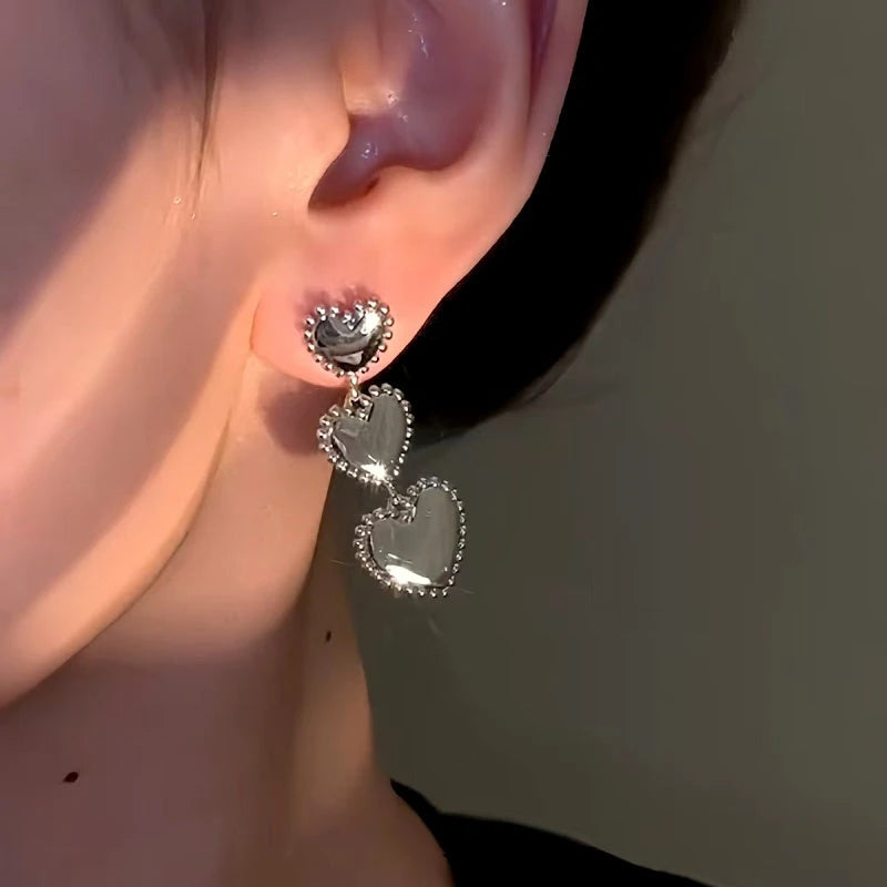 Model showcasing the dangle and style of the 14K Gold-Plated Heart-Design Earrings