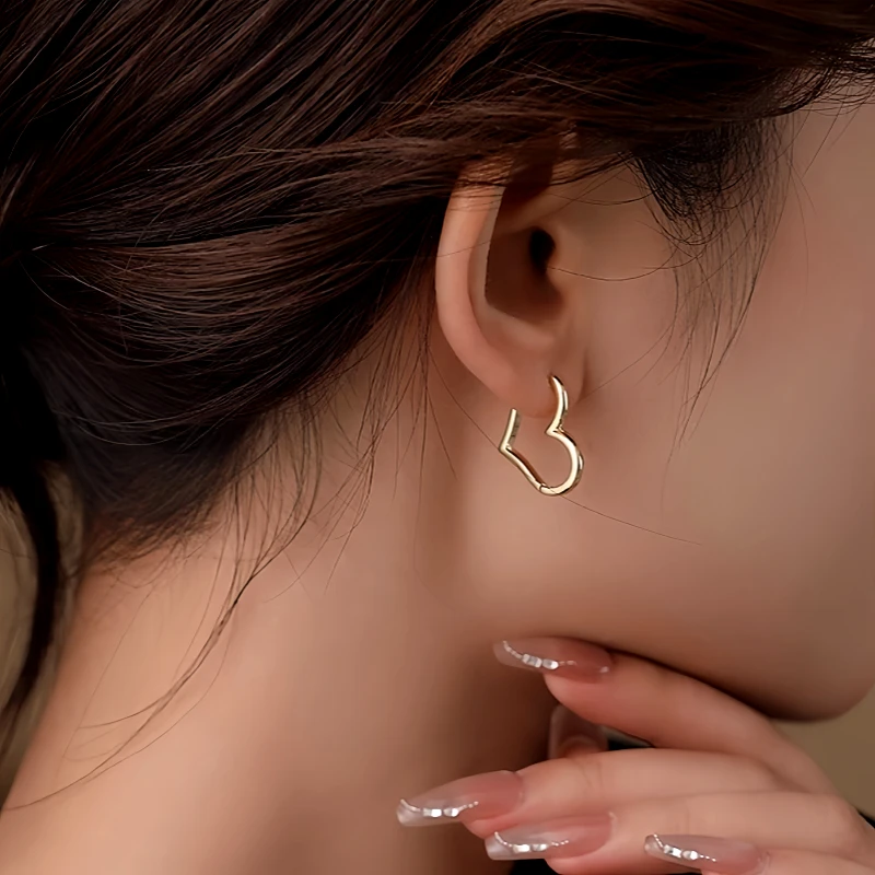Model showcasing the dangle and style of the 14K Gold-Plated Heart-Design Earrings