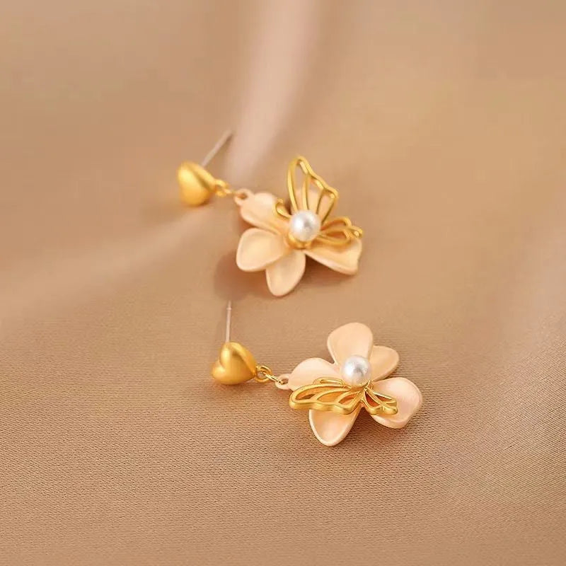 Model showcasing the dangle and style of the 14K Gold-Plated Heart-Design Flower Earrings