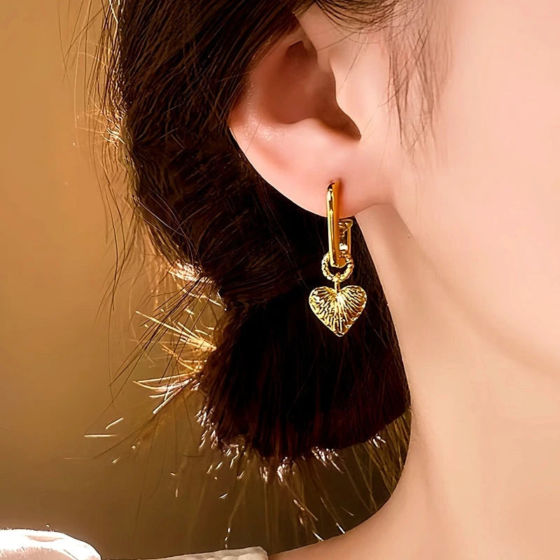 Model showcasing the dangle and style of the 14K Gold-Plated Heart-Design Pendant Earrings