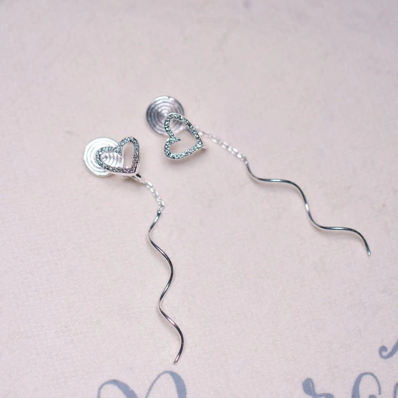 Model showcasing the dangle and style of the 14K Gold-Plated Heart Design Ear Clip Tassel Earrings