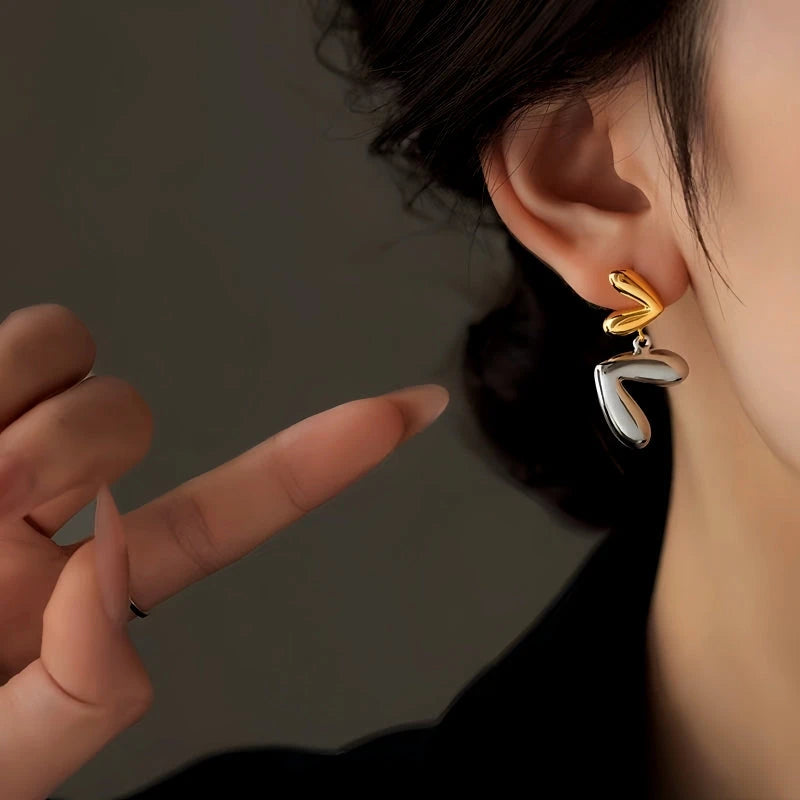 Model showcasing the dangle and style of the 14K Gold-Plated Heart Earrings