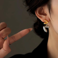 Model showcasing the dangle and style of the 14K Gold-Plated Heart Earrings