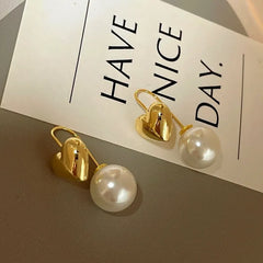Model showcasing the dangle and style of the 14K Gold-Plated Heart Pearl Earrings