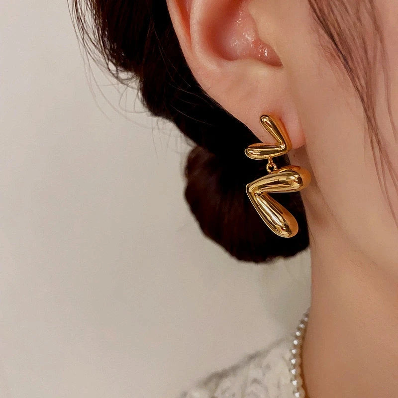 Model showcasing the dangle and style of the 14K Gold-Plated Heart Tassel Earrings