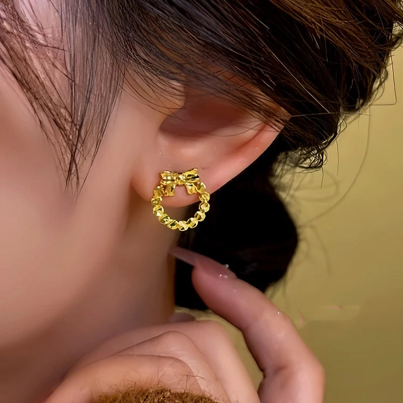 Model showcasing the dangle and style of the 14K Gold-Plated Hollow Bow Hoop Stud Earrings