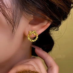 Model showcasing the dangle and style of the 14K Gold-Plated Hollow Bow Hoop Stud Earrings