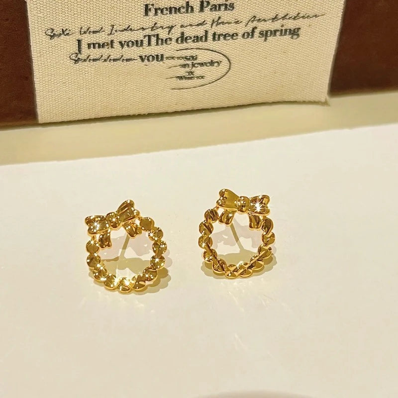 Angled view of the 14K Gold-Plated Hollow Bow Hoop Stud Earrings