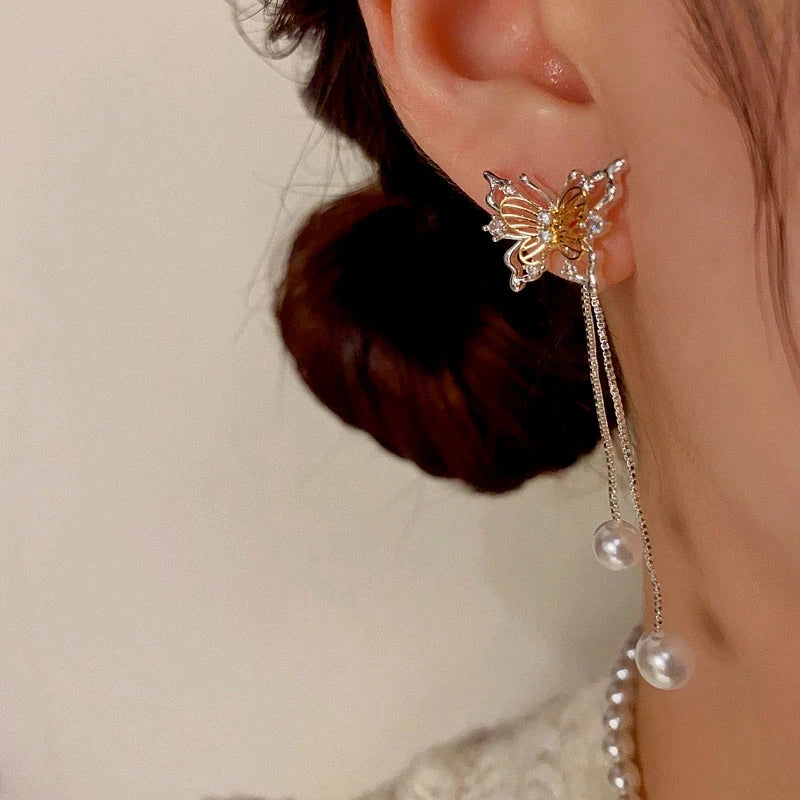 Model showcasing the dangle and style of the 14K Gold-Plated Hollow Butterfly Pearl Tassel Earrings