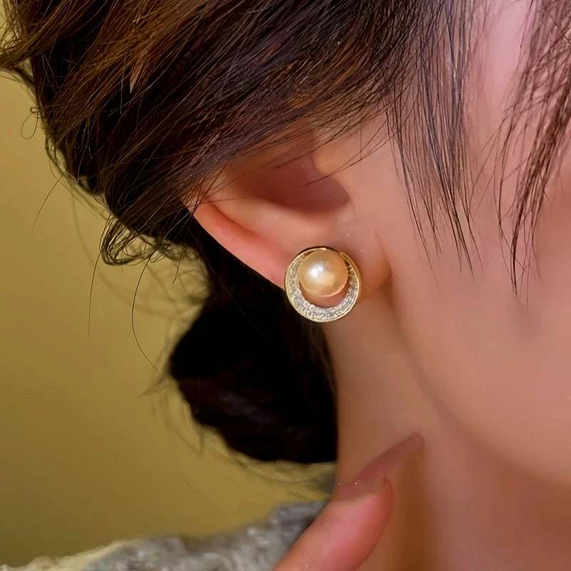 Model showcasing the dangle and style of the 14K Gold-Plated Hollow Diamond Pearl Stud Earrings