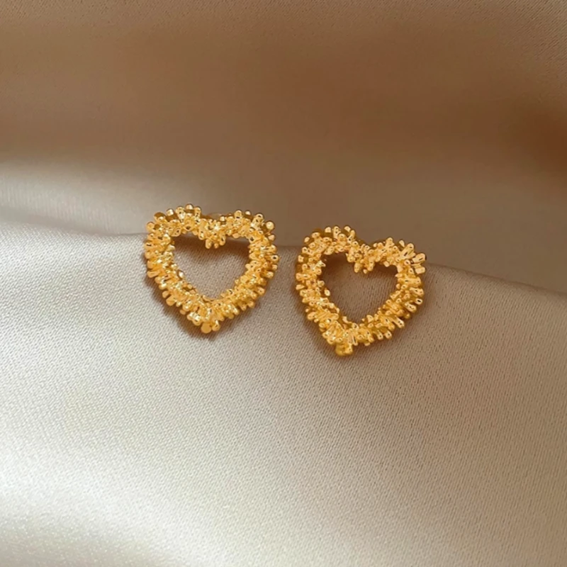 Model showcasing the dangle and style of the 14K Gold-Plated Hollow Heart Stud Earrings