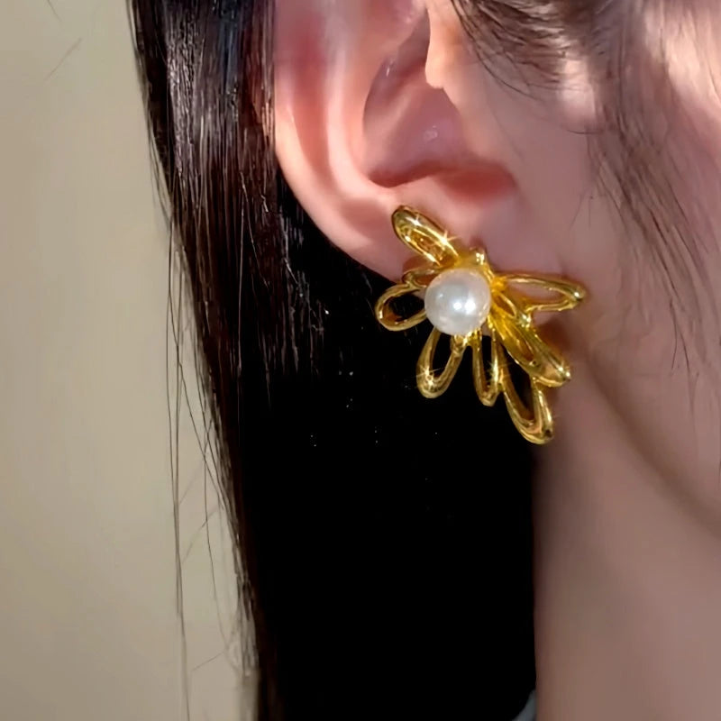 Model showcasing the dangle and style of the 14K Gold-Plated Hollow Metal Flower Pearl Earrings