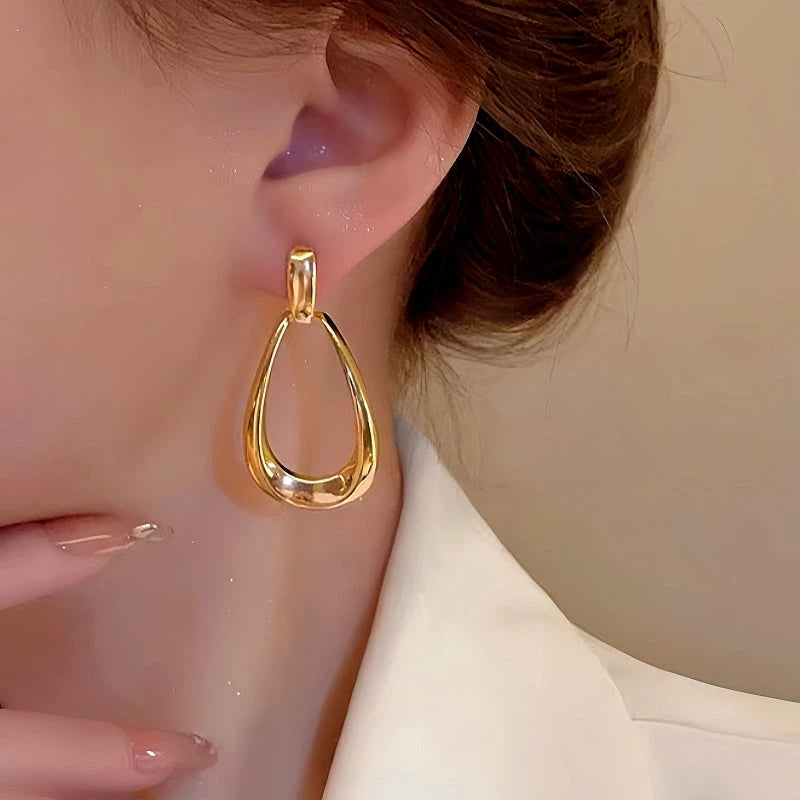 Model showcasing the dangle and style of the 14K Gold-Plated Hollow Water Drop Earrings