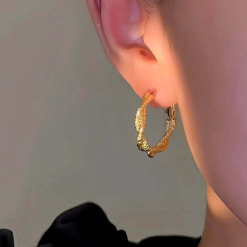 Model showcasing the dangle and style of the 14K Gold-Plated Irregular Twist Hoop Earrings
