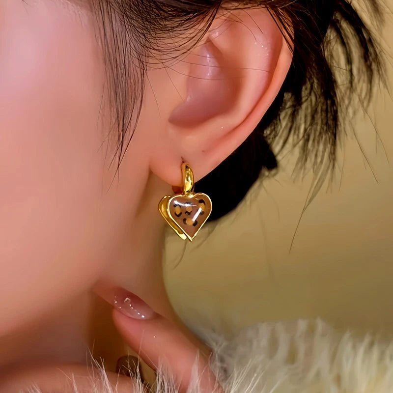Model showcasing the dangle and style of the 14K Gold-Plated Leopard Print Front And Back Heart Earrings