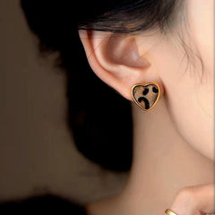 Model showcasing the dangle and style of the 14K Gold-Plated Leopard Print Small Heart Stud Earrings
