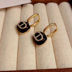 Model showcasing the dangle and style of the 14K Gold-Plated Letter CD Oil Drop Earrings