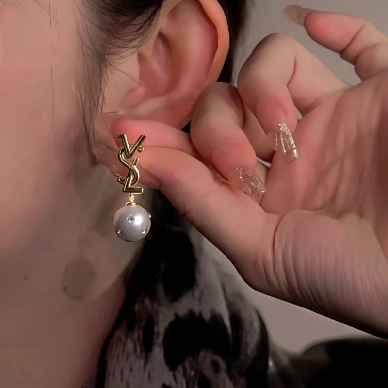 Model showcasing the dangle and style of the 14K Gold-Plated Letter Diamond Pearl Earrings