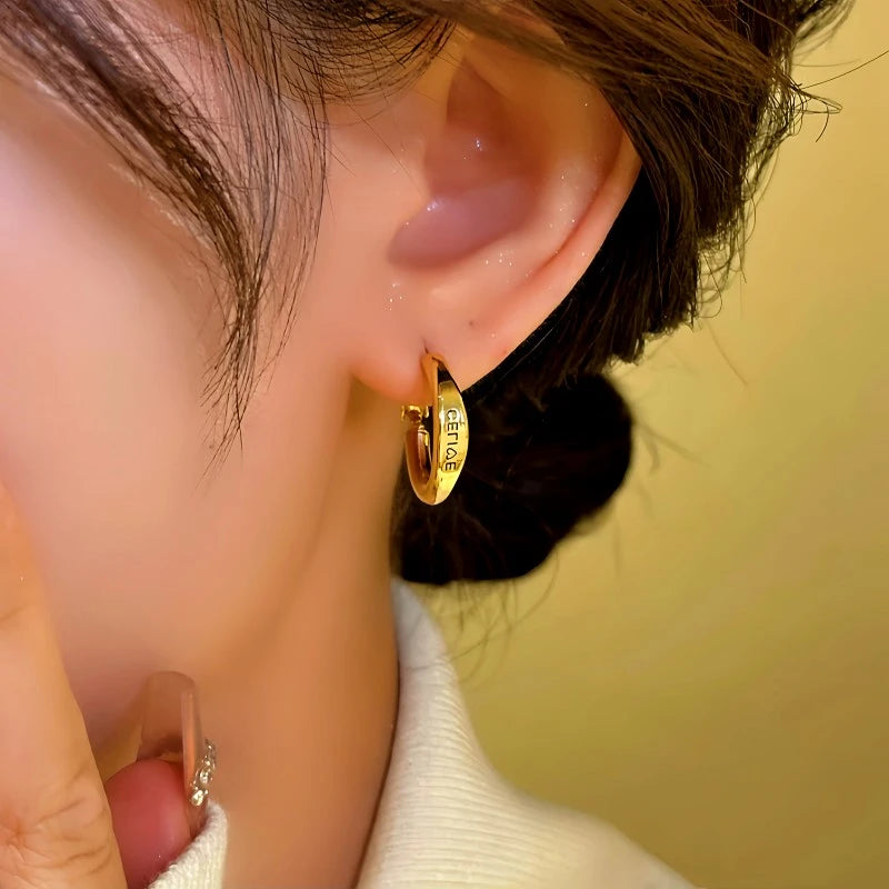 Model showcasing the dangle and style of the 14K Gold-Plated Letter Hoop Earrings
