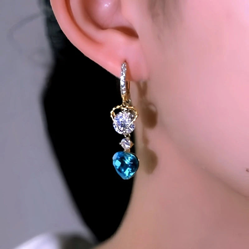 Model showcasing the dangle and style of the 14K Gold-Plated Luxury Blue Crystal Heart Tassel Earrings