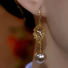 Model showcasing the dangle and style of the 14K Gold-Plated Luxury Brow Diamond Leaf Pearl Tassel Earrings