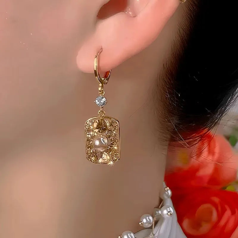 Model showcasing the dangle and style of the 14K Gold-Plated Luxury Brown Diamond Pearl Earrings