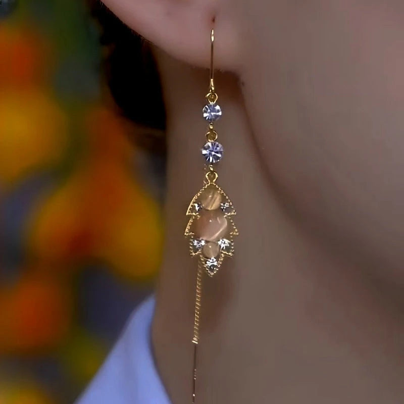 Model showcasing the dangle and style of the 14K Gold-Plated Luxury Cat's Eye Leaf Threader Earrings