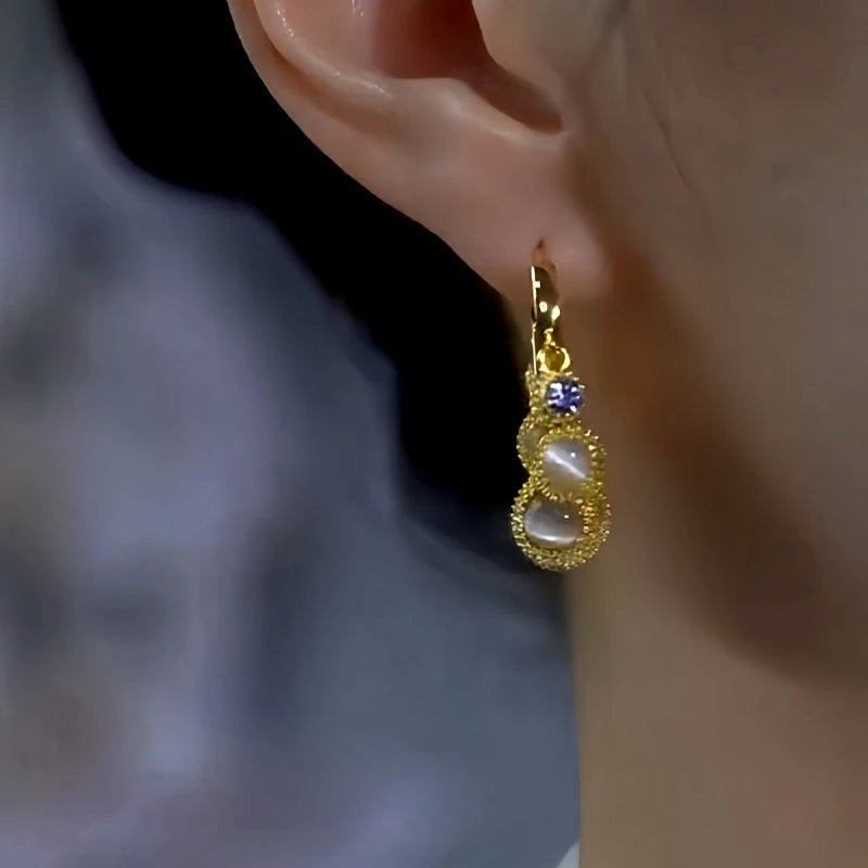 Model showcasing the dangle and style of the 14K Gold-Plated Luxury Cat's Eye Stone Durian Ball Earrings