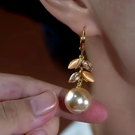 Model showcasing the dangle and style of the 14K Gold-Plated Luxury Cat's Eye Stone Leaf Pearl Earrings