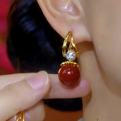 Model showcasing the dangle and style of the 14K Gold-Plated Luxury Diamond-Studded Red Pearl Earrings