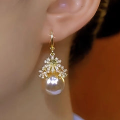 Model showcasing the dangle and style of the 14K Gold-Plated Luxury Diamond Flower Pearl Earrings