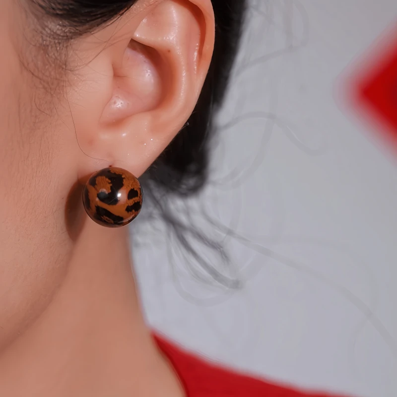 Model showcasing the dangle and style of the 14K Gold-Plated Luxury Leopard Print Ball Jacket Earrings