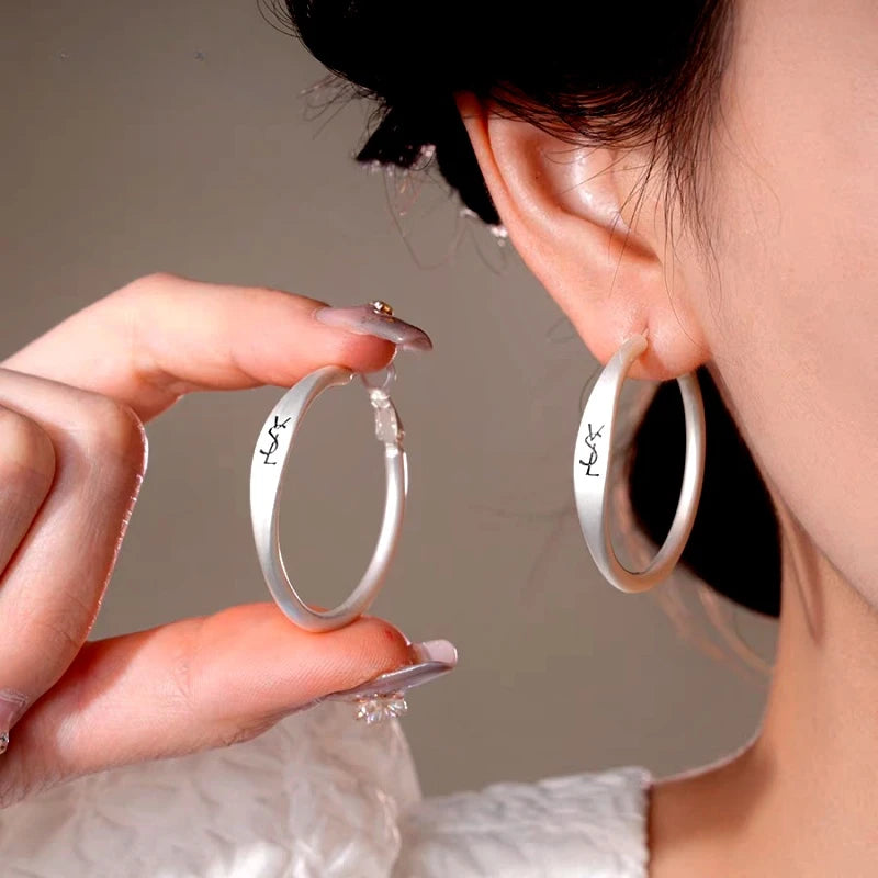 Model showcasing the dangle and style of the 14K Gold-Plated Luxury Letter Big Hoop Earrings