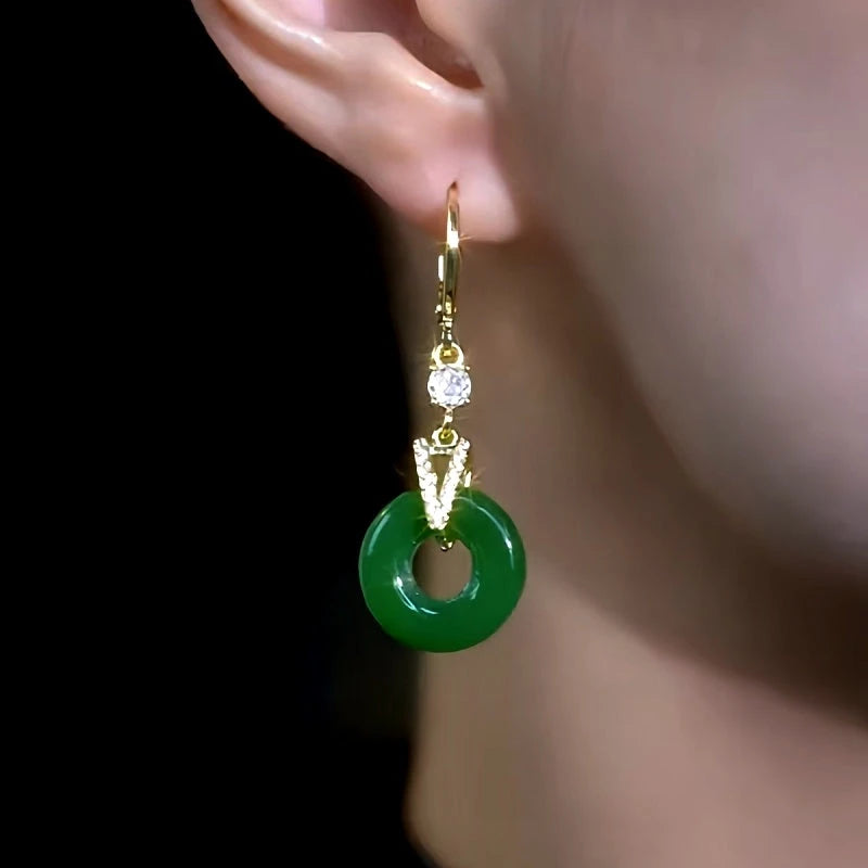 Side angle of gold green jade donut drop earring worn on ear