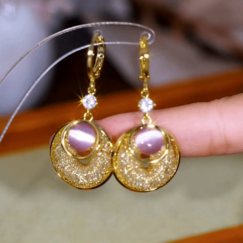 Model showcasing the dangle and style of the 14K Gold-Plated Luxury Pink Cat's Eye Stone Earrings