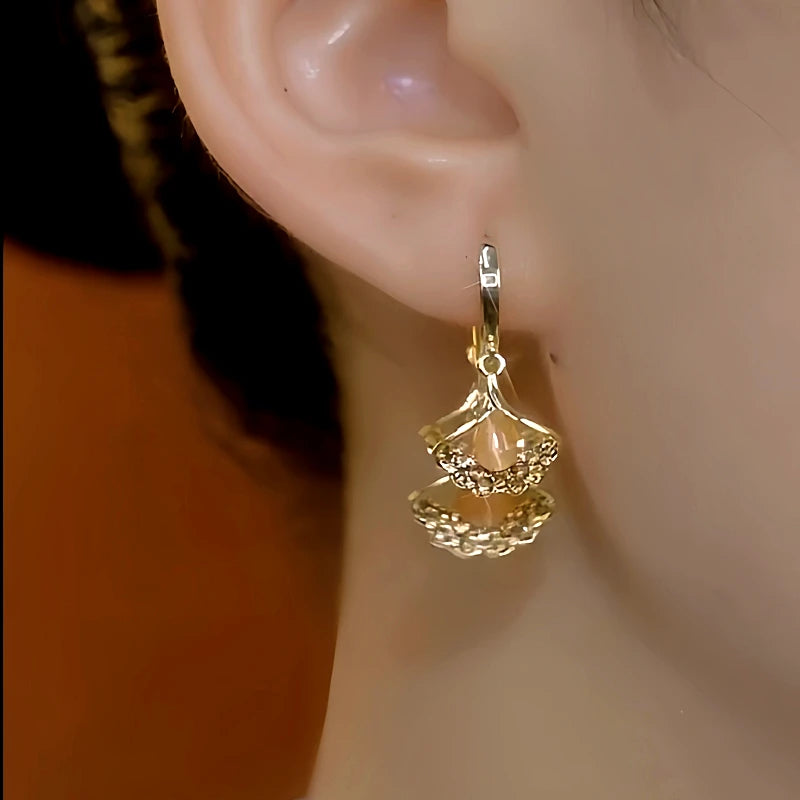 Model showcasing the dangle and style of the 14K Gold-Plated Luxury Three-Piece Ginkgo Leaf Earrings