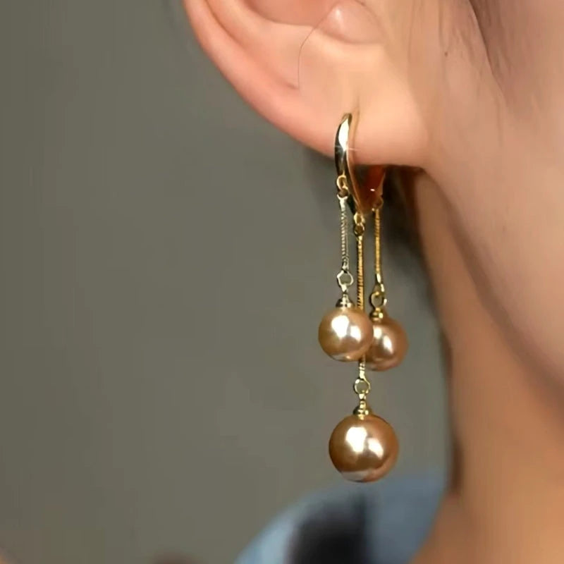 Model showcasing the dangle and style of the 14K Gold-Plated Luxury Three Champagne Gold Pearl Tassel Earrings