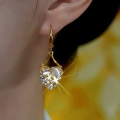 Model showcasing the dangle and style of the 14K Gold-Plated Luxury Zircon Cat's Eye Stone Heart Earrings