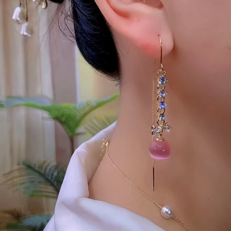 Rose gold pink bead crystal bow long dangle earring worn on ear closeup