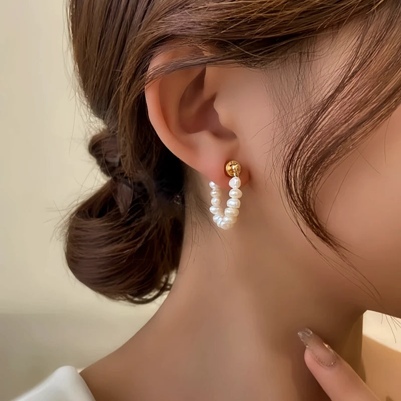 Side view of small freshwater pearl hoop earring with gold ball stud on woman’s ear