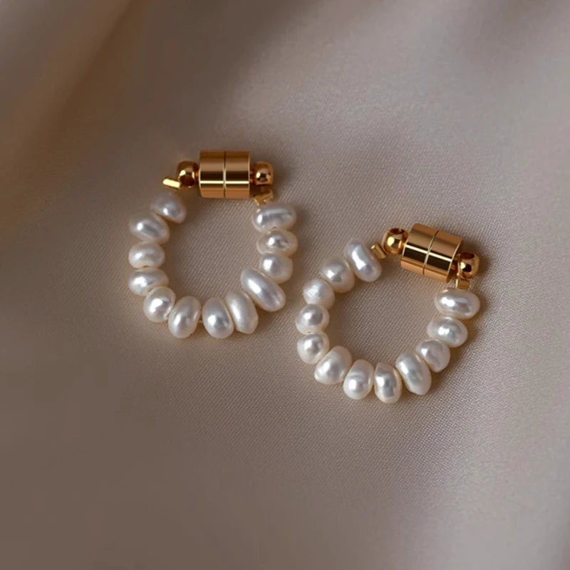 Pair of freshwater pearl hoop earrings with gold magnetic clasp on beige satin