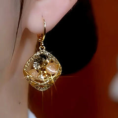 Gold champagne crystal square drop earring worn on ear close-up