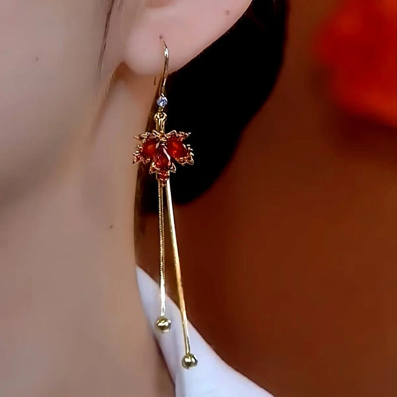 Side view of red maple leaf gold tassel long dangle earring worn on ear