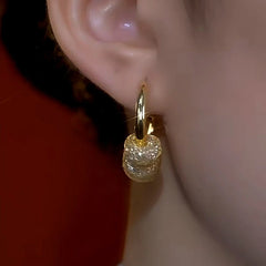 Close-up of gold mesh crystal dangle hoop earring worn on ear