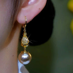 Front view of gold pave teardrop pearl drop dangle earring on ear