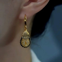 Matching gold two-tier textured teardrop hoop dangle earring on opposite ear, close-up