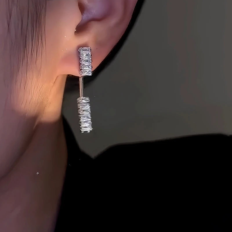 Sparkling silver crystal drop earring worn on ear, front close-up
