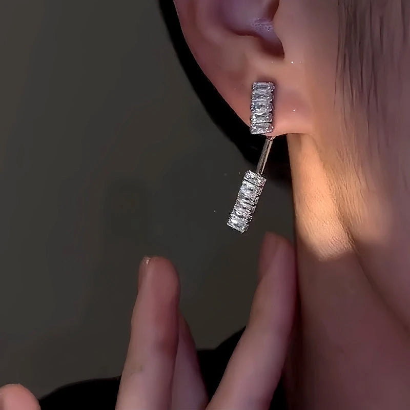 Silver crystal bar drop earring worn on earlobe, side close-up view