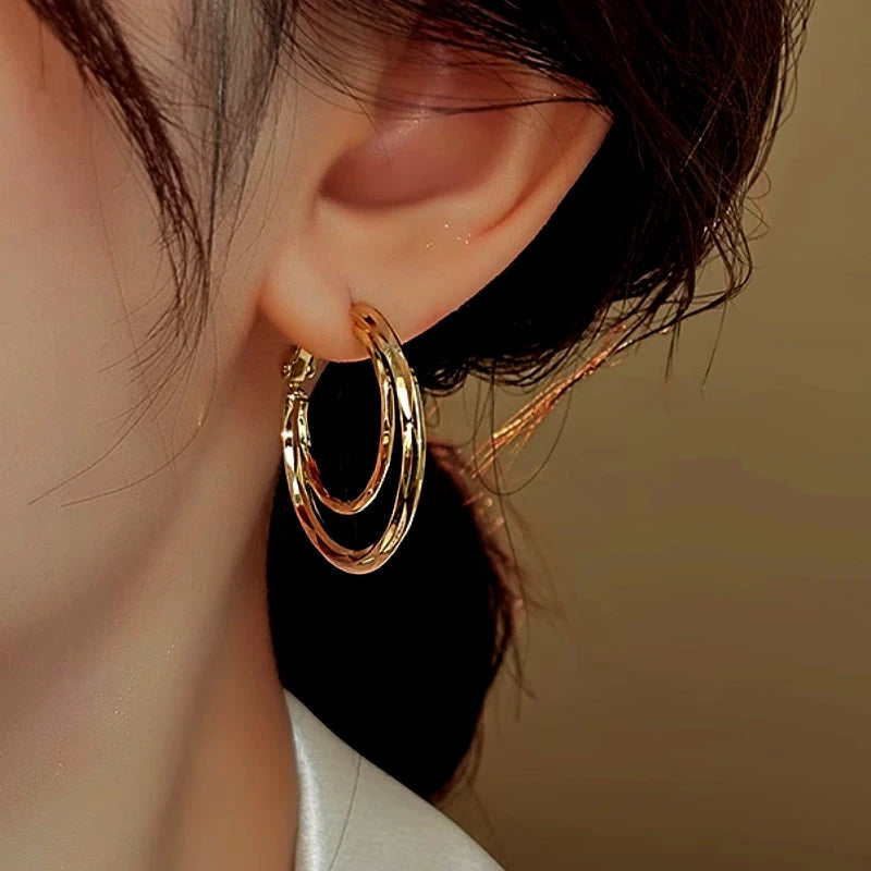 Close-up of gold double hoop earring worn on a woman's ear